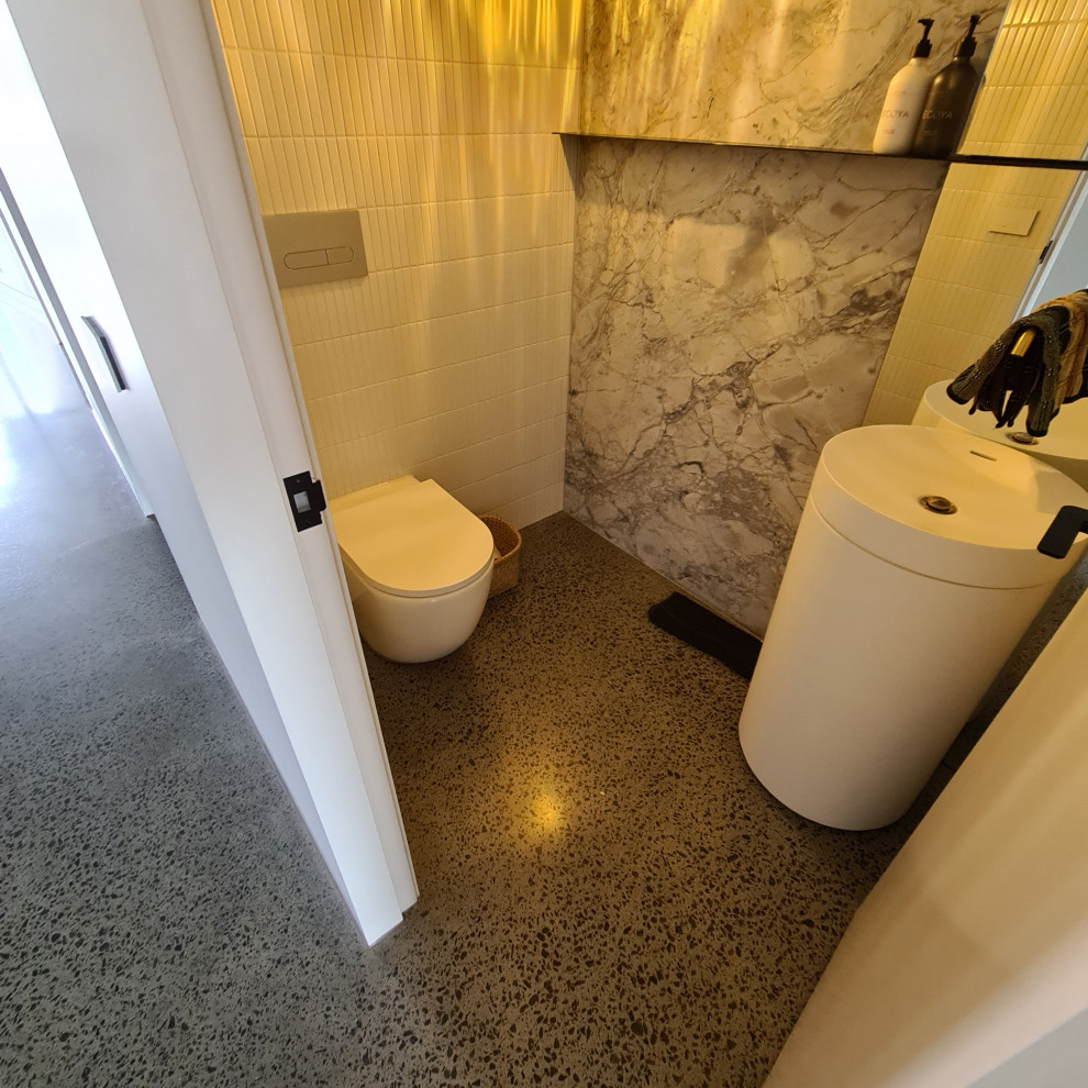 Mittelgroße Moderne Gästetoilette mit weißen Schränken, Wandtoilette, weißen Fliesen, Marmorfliesen, weißer Wandfarbe, Betonboden, grauem Boden und freistehendem Waschtisch in Melbourne