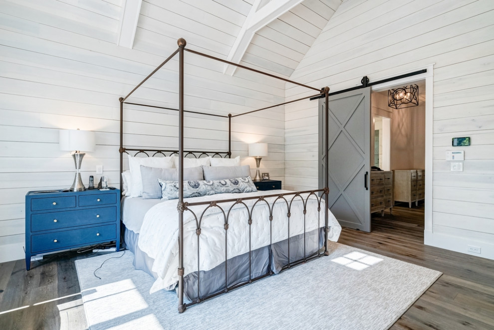 Inspiration pour une chambre parentale minimaliste avec un mur blanc, un manteau de cheminée en pierre, un plafond voûté et du lambris de bois.