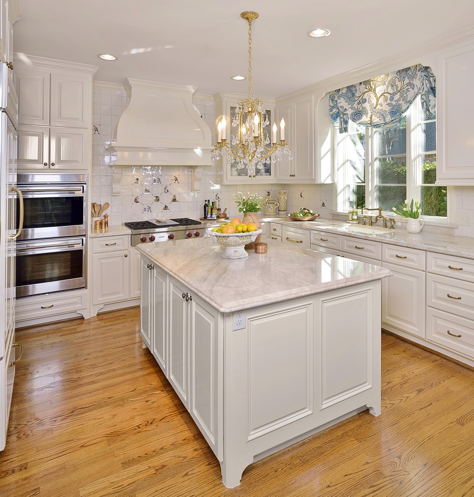 This is an example of a traditional u-shaped eat-in kitchen in Houston with an undermount sink, raised-panel cabinets, white cabinets, quartzite benchtops, white splashback, ceramic splashback, stainless steel appliances and medium hardwood floors.