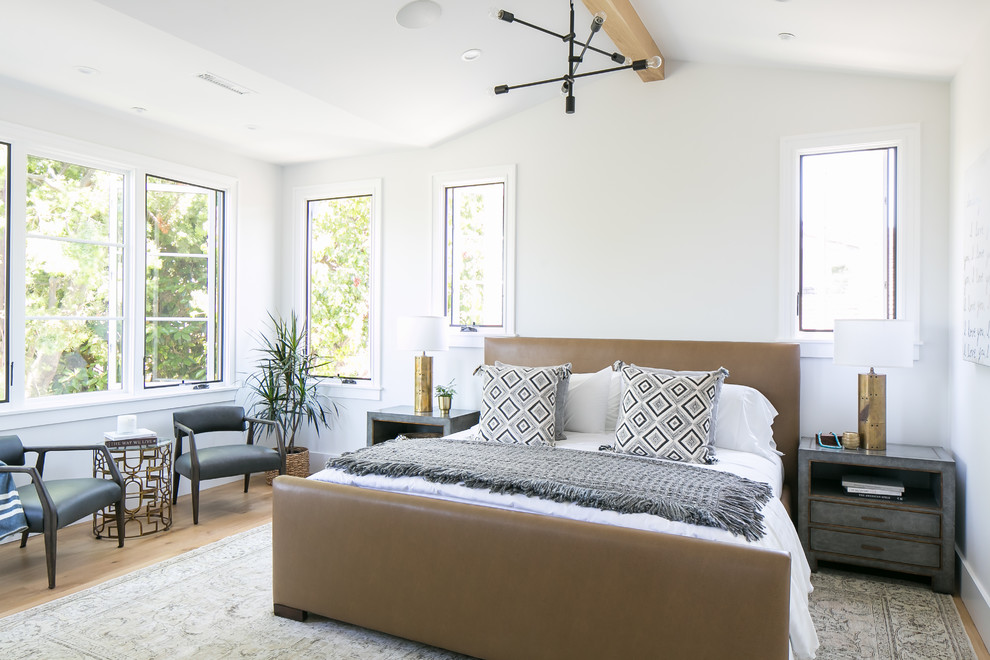 This is an example of a transitional bedroom in Orange County with white walls, medium hardwood floors and brown floor.