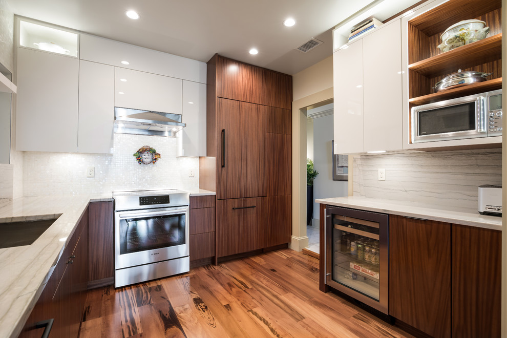 This is an example of a mid-sized contemporary u-shaped eat-in kitchen in Jacksonville with an undermount sink, flat-panel cabinets, white cabinets, quartzite benchtops, limestone splashback, stainless steel appliances, medium hardwood floors, no island, multi-coloured floor and white benchtop.