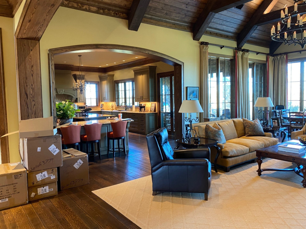 Large open concept living room with beige walls, dark hardwood floors, brown floor and exposed beam.
