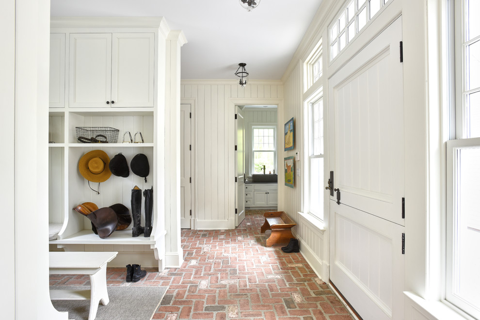 Design ideas for a traditional mudroom in New York with white walls, brick floors, a dutch front door, a white front door and pink floor.
