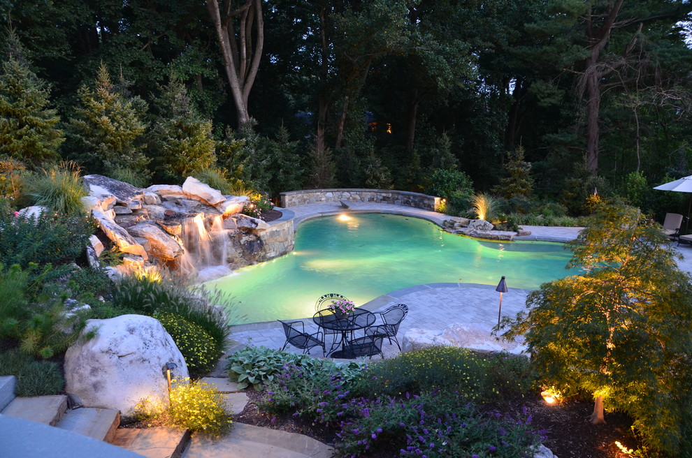 Mid-sized traditional backyard custom-shaped lap pool in DC Metro with a water feature and concrete pavers.