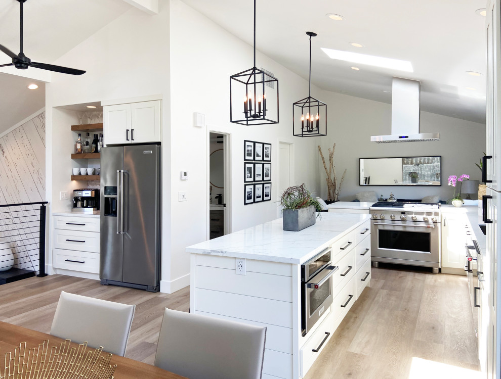 Inspiration for a mid-sized transitional l-shaped eat-in kitchen in Other with an undermount sink, shaker cabinets, white cabinets, quartz benchtops, multi-coloured splashback, mosaic tile splashback, stainless steel appliances, vinyl floors, with island, brown floor, white benchtop and vaulted.
