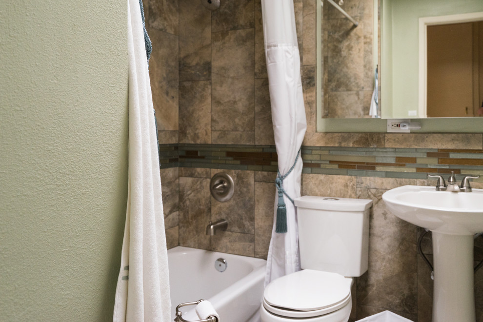 Modelo de cuarto de baño único de estilo americano de tamaño medio con paredes beige, lavabo con pedestal, bañera empotrada, combinación de ducha y bañera y ducha con cortina