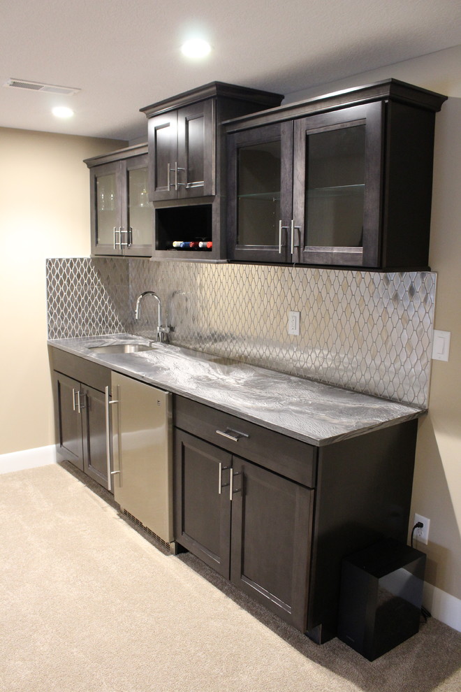 Large modern single-wall wet bar in Cleveland with carpet, an undermount sink, recessed-panel cabinets, dark wood cabinets, granite benchtops and metal splashback.