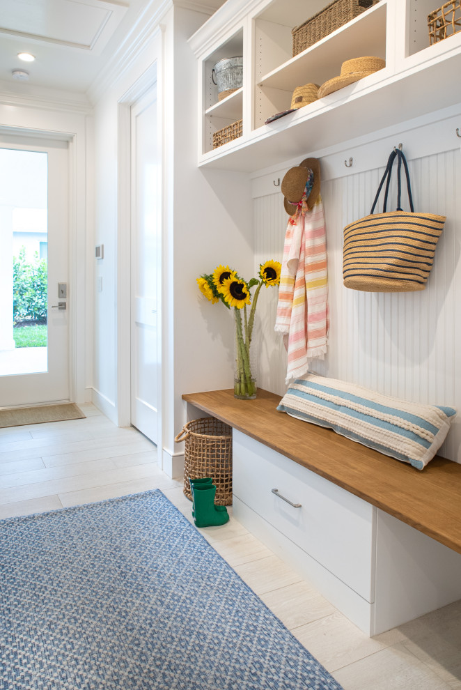 Photo of a mid-sized beach style mudroom in Miami with white walls, ceramic floors, a single front door, a white front door, white floor and decorative wall panelling.