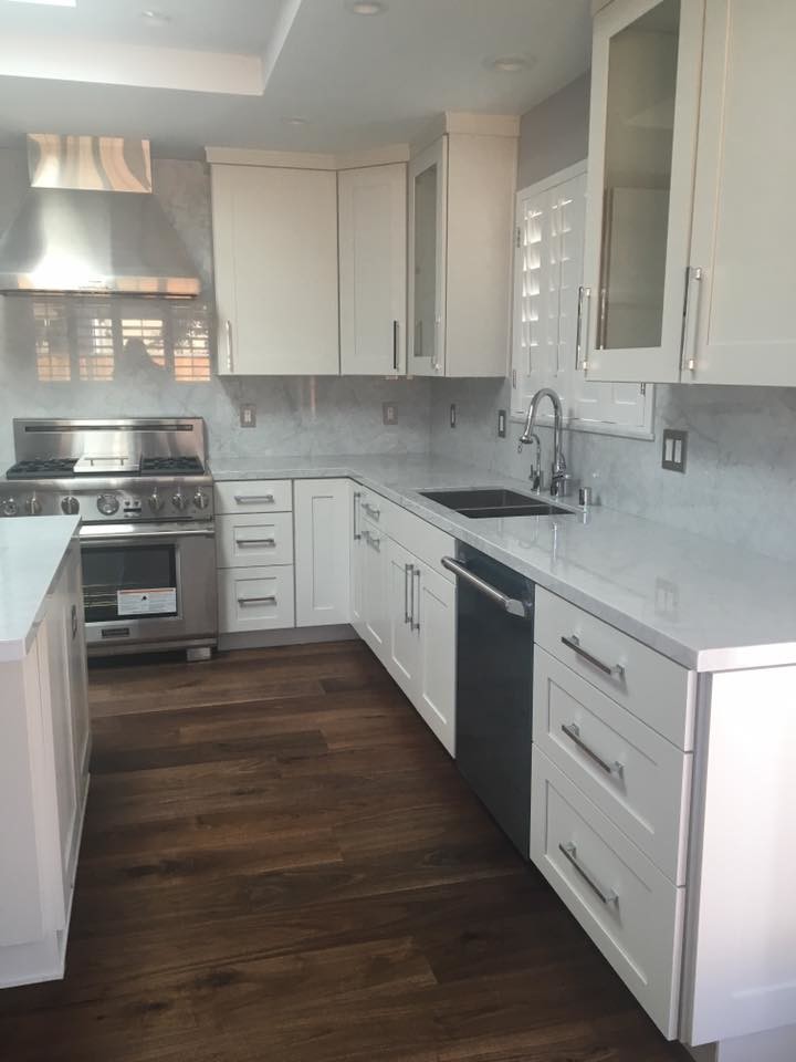 Mid-sized contemporary l-shaped kitchen in San Francisco with a double-bowl sink, shaker cabinets, white cabinets, quartzite benchtops, dark hardwood floors, with island, brown floor, grey splashback, stone slab splashback and stainless steel appliances.