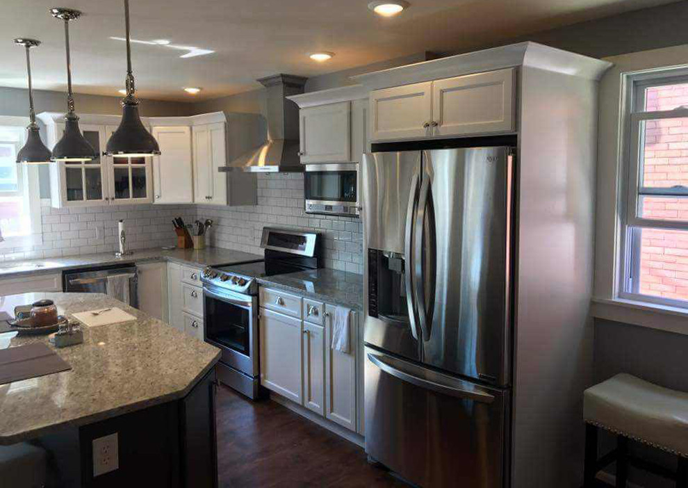 Large transitional l-shaped medium tone wood floor and brown floor eat-in kitchen photo with shaker cabinets, white cabinets, granite countertops, white backsplash, subway tile backsplash, stainless steel appliances, an island, beige countertops and an undermount sink