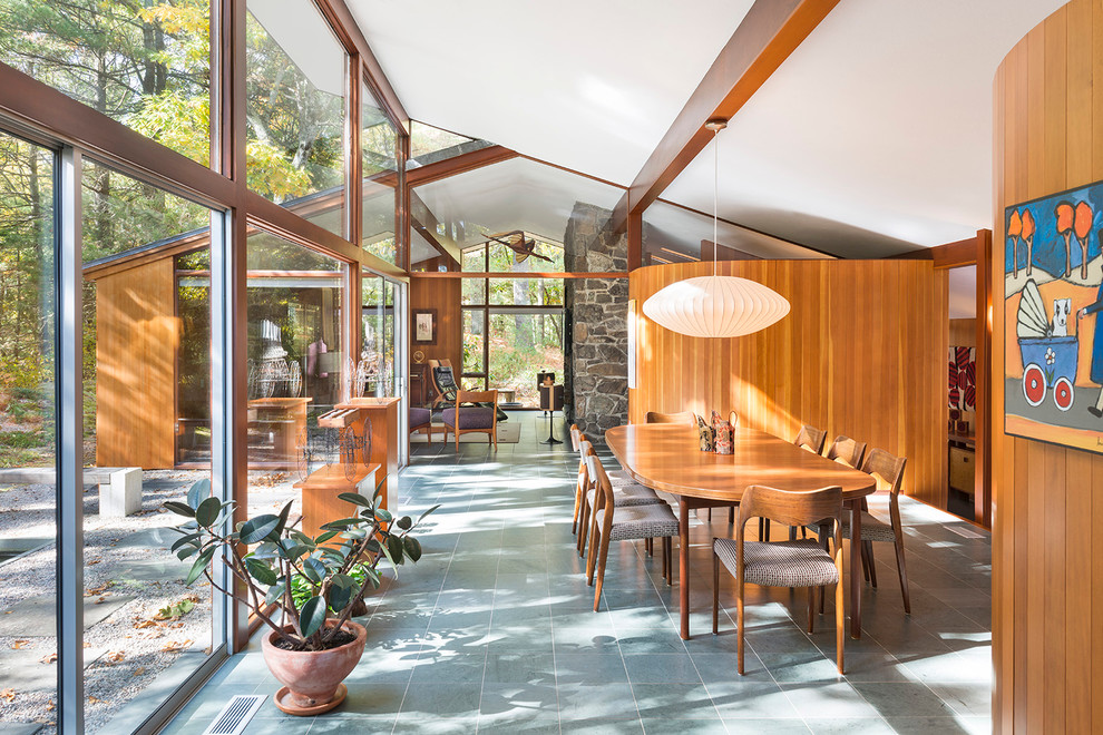 This is an example of a large midcentury open plan dining in Boston with slate floors and brown walls.