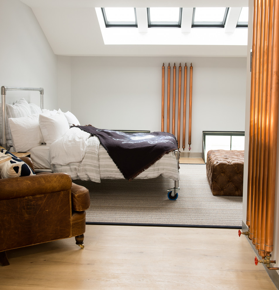 Industrial bedroom in London with white walls and light hardwood floors.