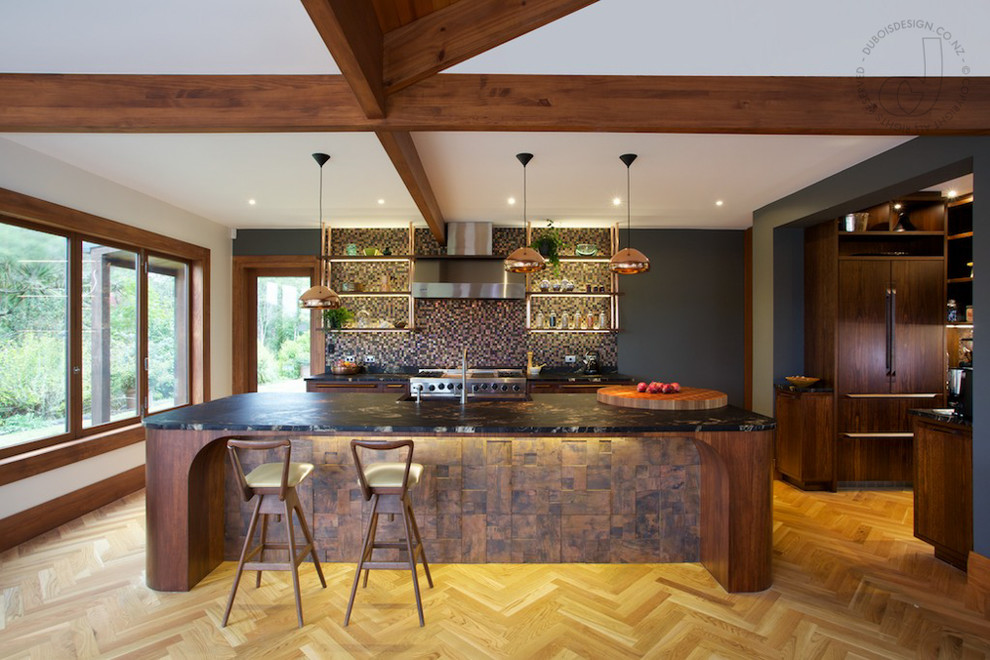 Photo of a large contemporary u-shaped eat-in kitchen in Auckland with a farmhouse sink, raised-panel cabinets, medium wood cabinets, granite benchtops, multi-coloured splashback, mosaic tile splashback, stainless steel appliances, light hardwood floors and with island.