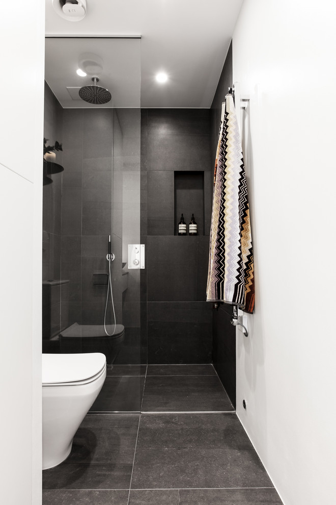 Mid-sized modern bathroom in Stockholm with black tile, slate floors, black floor and a corner shower.