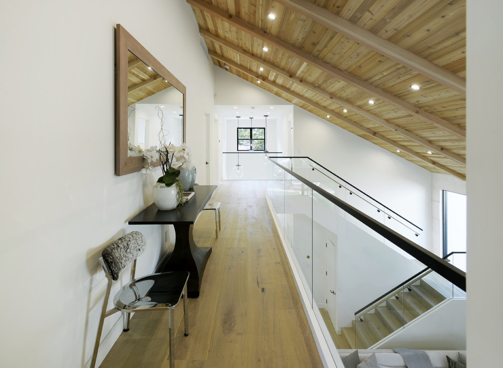 Inspiration for a contemporary hallway in Los Angeles with white walls, light hardwood floors and brown floor.