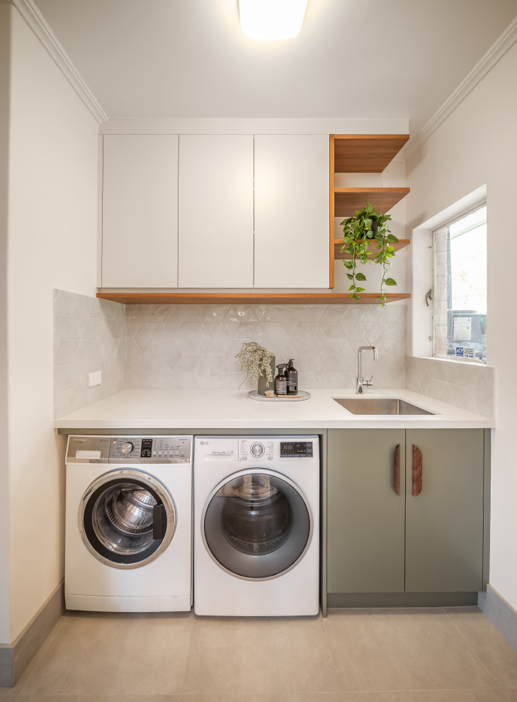 Design ideas for a small contemporary single-wall dedicated laundry room in Adelaide with an undermount sink, flat-panel cabinets, green cabinets, quartz benchtops, grey splashback, porcelain splashback, white walls, ceramic floors, a side-by-side washer and dryer, grey floor and white benchtop.