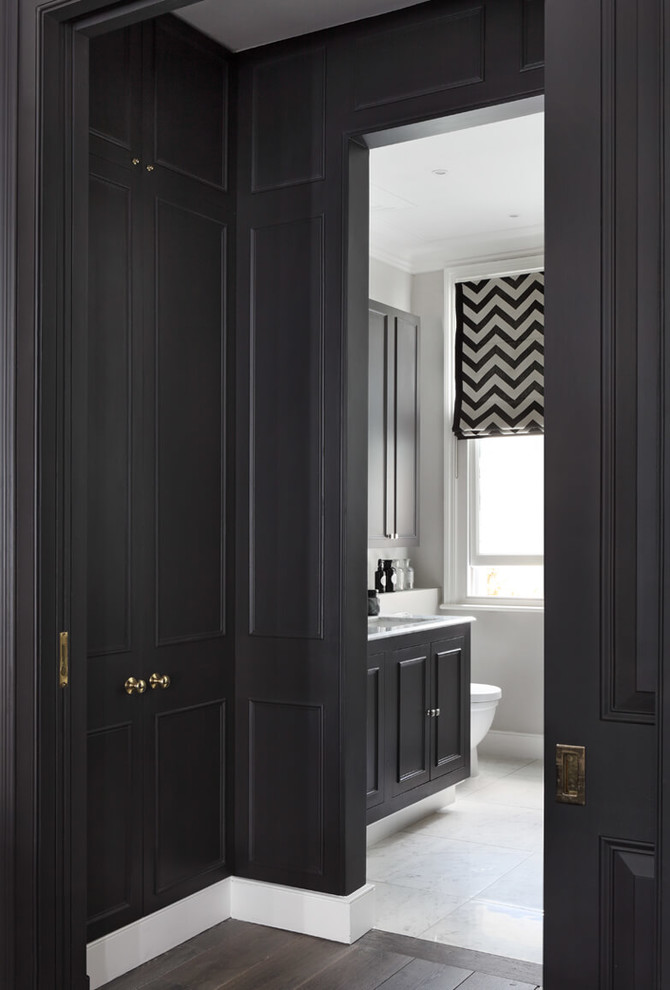 This is an example of a large contemporary gender-neutral walk-in wardrobe in London with raised-panel cabinets, black cabinets, medium hardwood floors and grey floor.