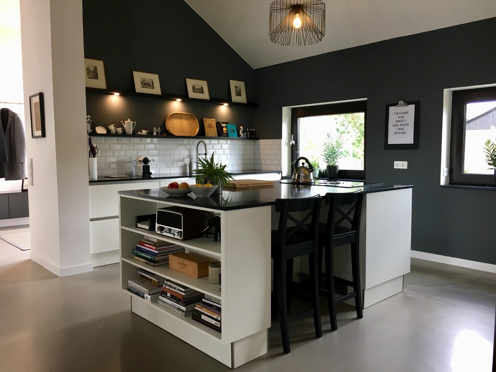 Inspiration for a mid-sized contemporary galley open plan kitchen in Hanover with a drop-in sink, flat-panel cabinets, quartz benchtops, with island, grey floor, white cabinets, white splashback, subway tile splashback, vinyl floors and black benchtop.