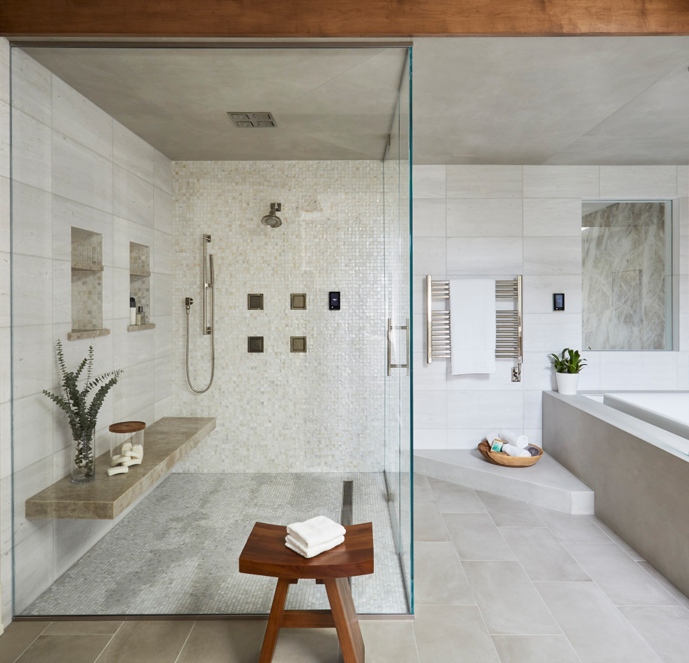 На фото: огромная главная ванная комната в стиле неоклассика (современная классика) с угловой ванной, двойным душем, бежевой плиткой, керамической плиткой, бежевыми стенами, полом из керамической плитки, серым полом, душем с распашными дверями, сиденьем для душа и балками на потолке