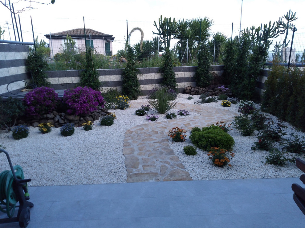 Imagen de jardín de secano moderno de tamaño medio en verano en patio trasero con paisajismo estilo desértico, exposición total al sol, adoquines de piedra natural y con metal