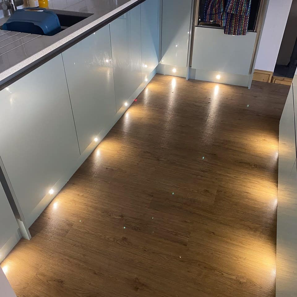 Medium sized contemporary open plan kitchen with a submerged sink, flat-panel cabinets, turquoise cabinets, quartz worktops, white splashback, metro tiled splashback, integrated appliances, vinyl flooring, an island, brown floors, white worktops and a feature wall.