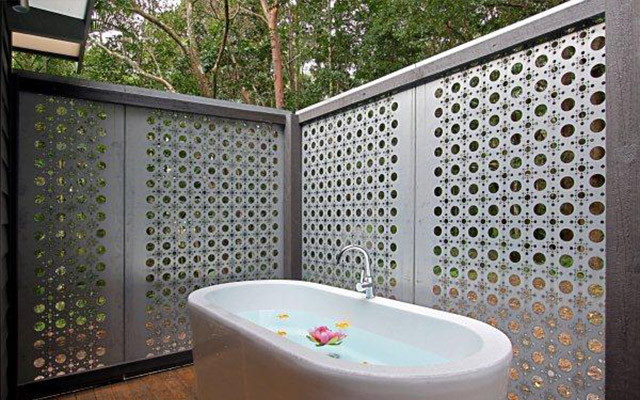 Inspiration for a mid-sized tropical bathroom in Gold Coast - Tweed with black tile, a freestanding tub, grey walls and brick floors.
