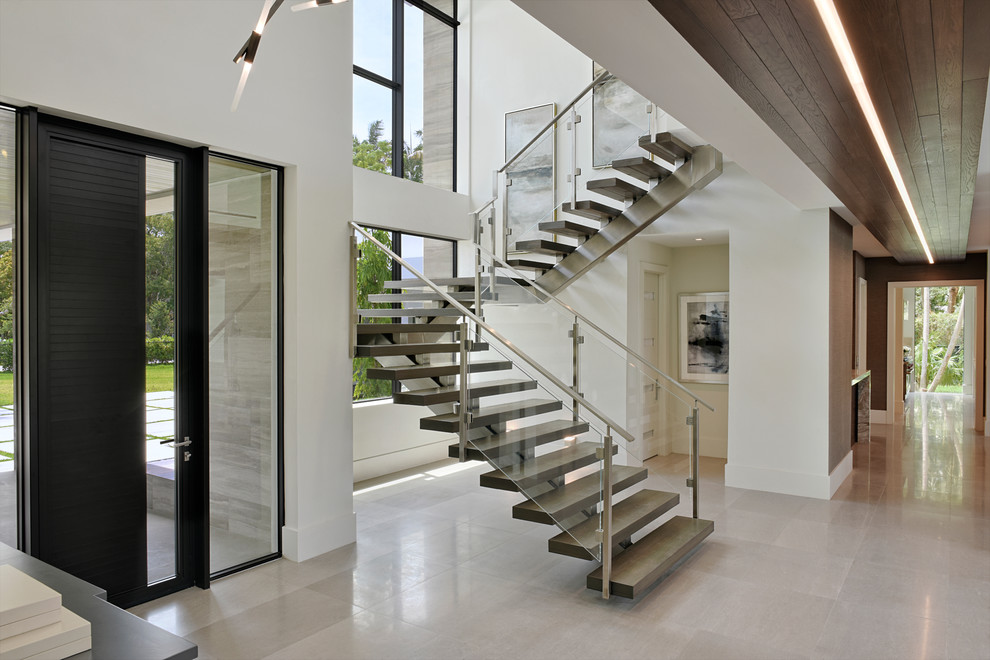 This is an example of a contemporary u-shaped staircase in Miami with open risers and glass railing.