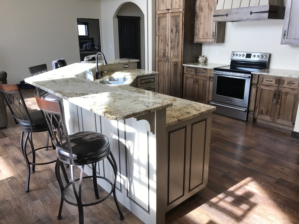 Open concept kitchen - large traditional dark wood floor and brown floor open concept kitchen idea with flat-panel cabinets, distressed cabinets, granite countertops, a double-bowl sink, stainless steel appliances and an island