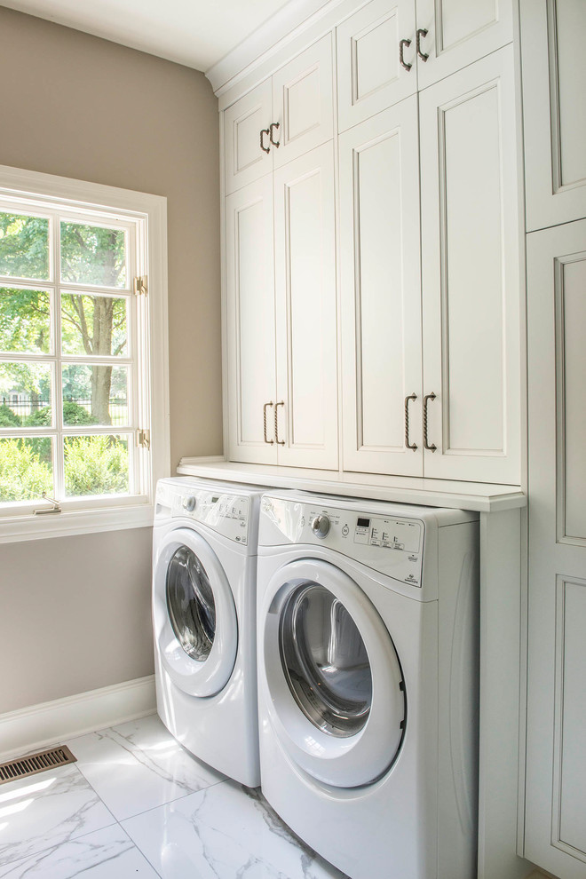 This is an example of a small transitional galley dedicated laundry room in Kansas City with an undermount sink, recessed-panel cabinets, white cabinets, beige walls, marble floors, a side-by-side washer and dryer, white floor and white benchtop.