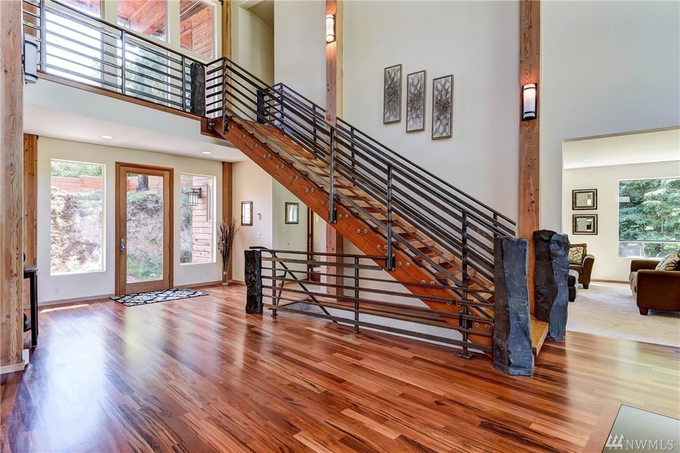 This is an example of a contemporary wood staircase in Seattle with open risers and metal railing.
