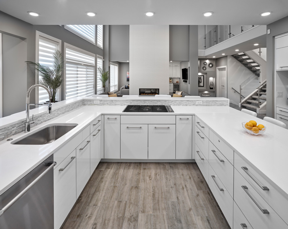 Inspiration for a mid-sized contemporary u-shaped kitchen pantry in Edmonton with an undermount sink, louvered cabinets, white cabinets, quartz benchtops, white splashback, stainless steel appliances, light hardwood floors, with island, brown floor and white benchtop.