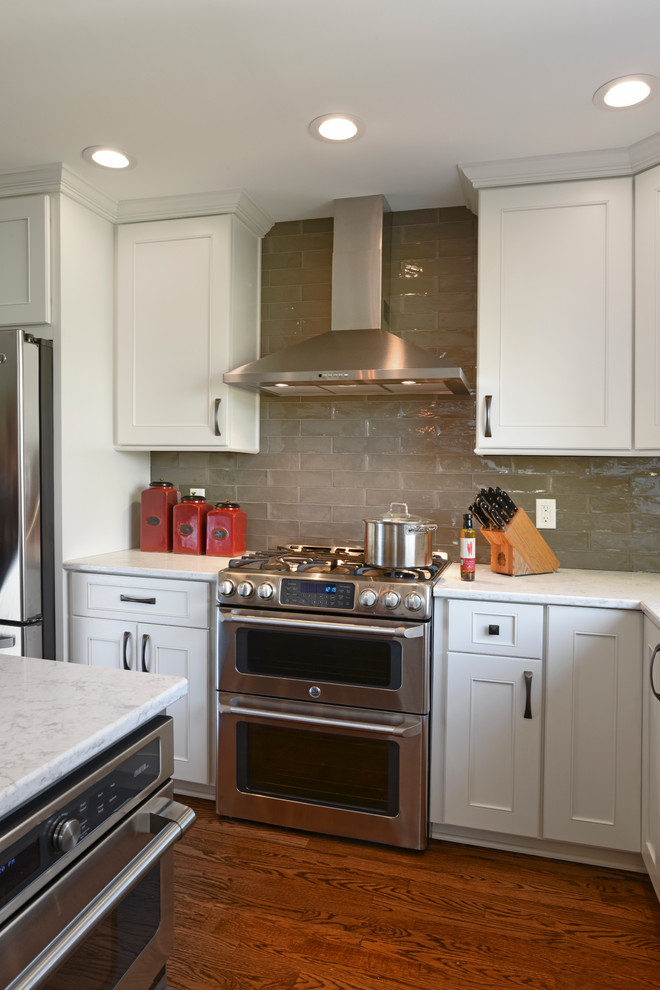 Inspiration for a transitional l-shaped medium tone wood floor eat-in kitchen remodel in Orange County with a double-bowl sink, shaker cabinets, white cabinets, marble countertops, gray backsplash, glass tile backsplash, stainless steel appliances and an island