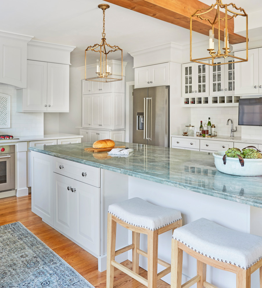 Large traditional l-shaped eat-in kitchen in Chicago with an undermount sink, raised-panel cabinets, white cabinets, quartzite benchtops, white splashback, mosaic tile splashback, stainless steel appliances, medium hardwood floors, with island, brown floor and blue benchtop.