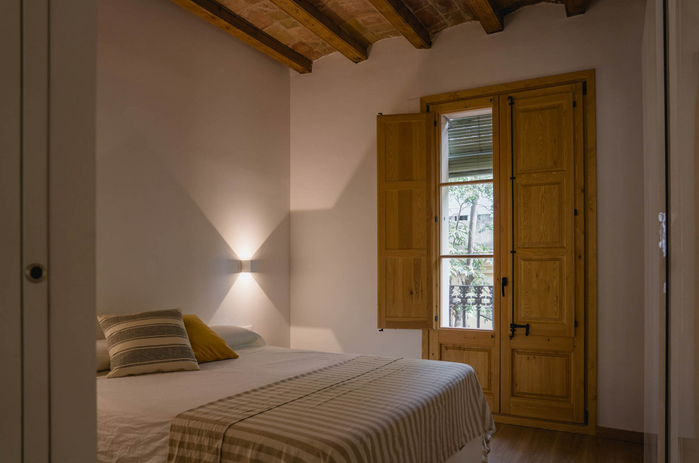 Esempio di una camera matrimoniale stile rurale di medie dimensioni con pareti bianche, pavimento in legno massello medio, pavimento marrone e travi a vista