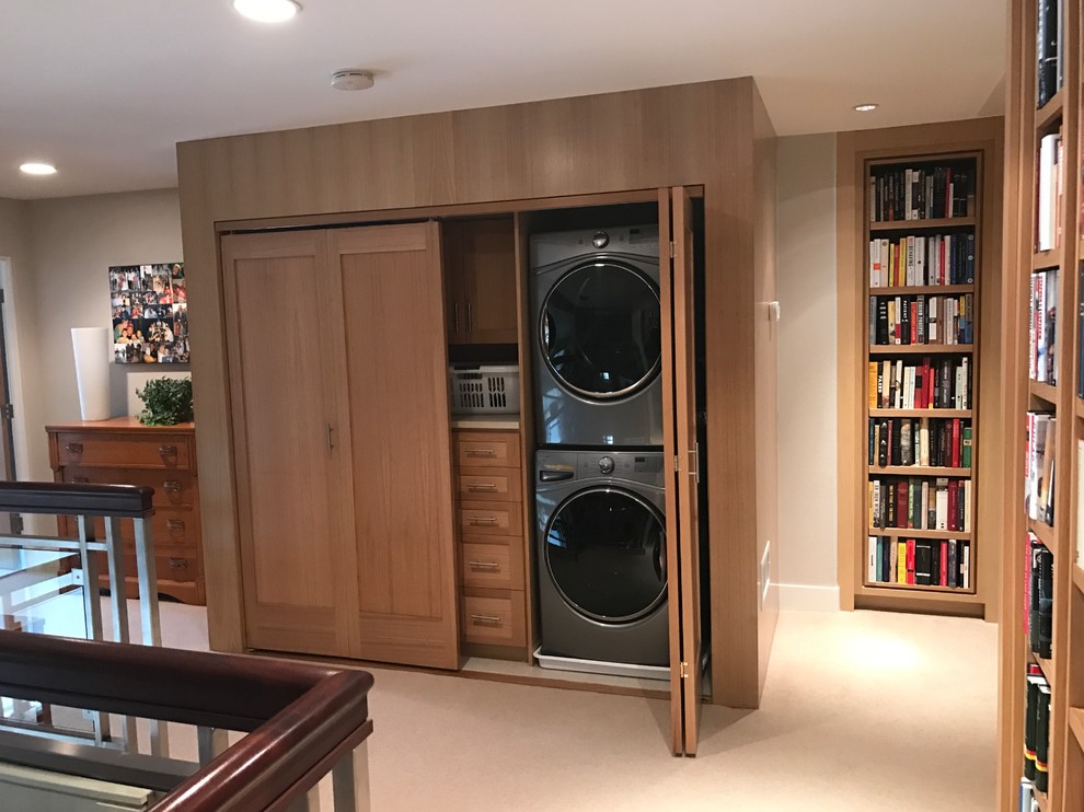 This is an example of a mid-sized traditional single-wall laundry cupboard in Orange County with shaker cabinets, medium wood cabinets, beige walls, porcelain floors and a concealed washer and dryer.