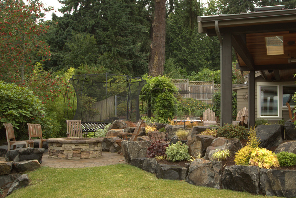 This is an example of a large traditional backyard patio in Seattle with a fire feature, natural stone pavers and no cover.