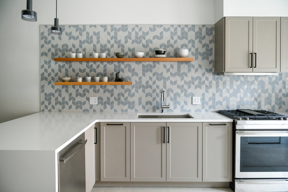 Transitional l-shaped kitchen photo with an undermount sink, shaker cabinets, gray cabinets, multicolored backsplash, stainless steel appliances and white countertops