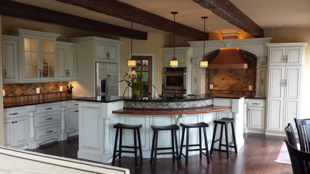 Inspiration for a mid-sized timeless l-shaped medium tone wood floor eat-in kitchen remodel in Indianapolis with an undermount sink, raised-panel cabinets, white cabinets, granite countertops, beige backsplash, cement tile backsplash, stainless steel appliances, yellow walls and an island