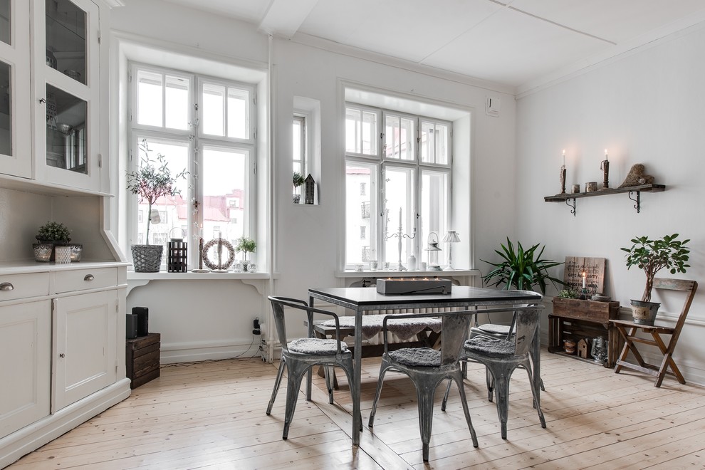 Design ideas for a mid-sized traditional dining room in Gothenburg with white walls, light hardwood floors and no fireplace.