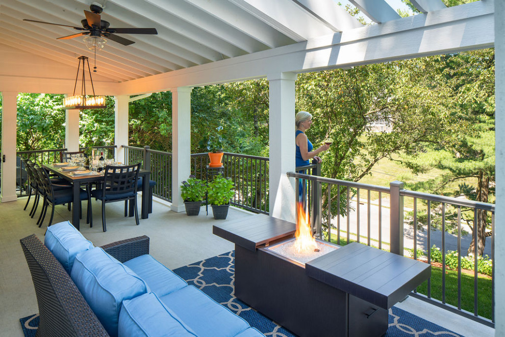 Design ideas for an expansive traditional front metal railing veranda in Columbus with a fire feature, concrete slabs and a roof extension.