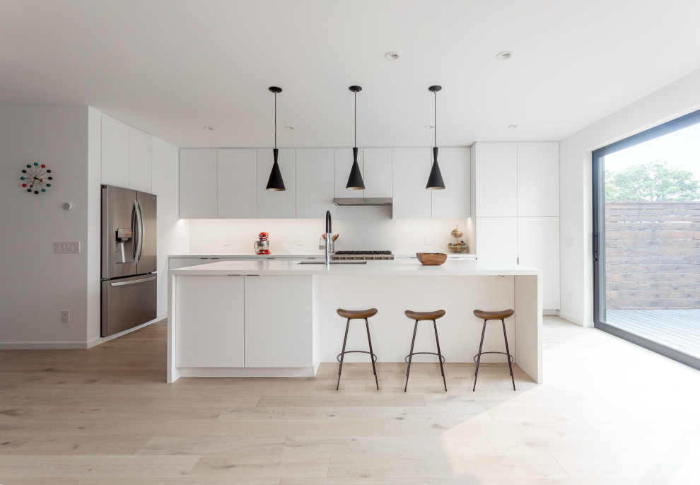 This is an example of a mid-sized modern u-shaped eat-in kitchen in San Francisco with an undermount sink, flat-panel cabinets, white cabinets, quartz benchtops, white splashback, stainless steel appliances, light hardwood floors, with island, white benchtop and glass sheet splashback.