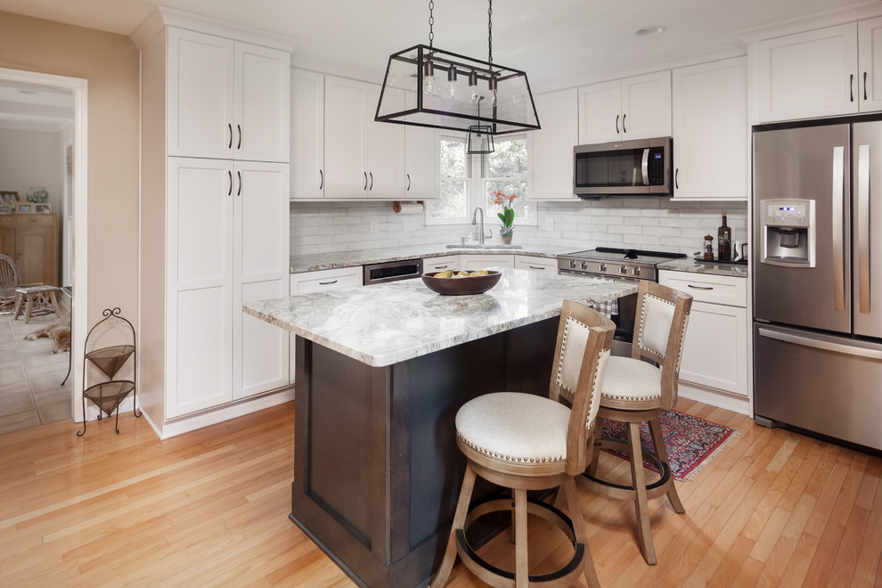 This is an example of a small transitional l-shaped kitchen in Charlotte with an undermount sink, marble benchtops, stainless steel appliances, light hardwood floors and with island.