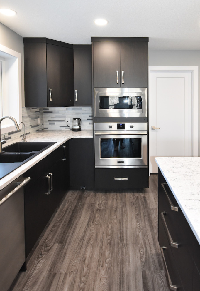 Modern inredning av ett mellanstort vit vitt kök, med en undermonterad diskho, släta luckor, skåp i mörkt trä, träbänkskiva, grått stänkskydd, stänkskydd i keramik, rostfria vitvaror, laminatgolv, en köksö och brunt golv
