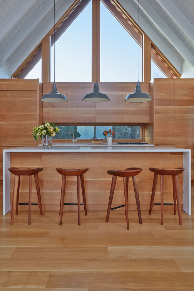 Eat-in kitchen - large coastal galley medium tone wood floor and brown floor eat-in kitchen idea in New York with an undermount sink, flat-panel cabinets, medium tone wood cabinets, paneled appliances, an island, quartz countertops and window backsplash