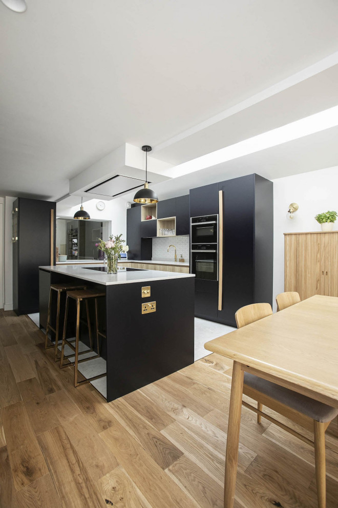 Inspiration for a small contemporary l-shaped open plan kitchen in London with an undermount sink, beaded inset cabinets, black cabinets, quartzite benchtops, white splashback, ceramic splashback, black appliances, ceramic floors, with island, multi-coloured floor, white benchtop and vaulted.