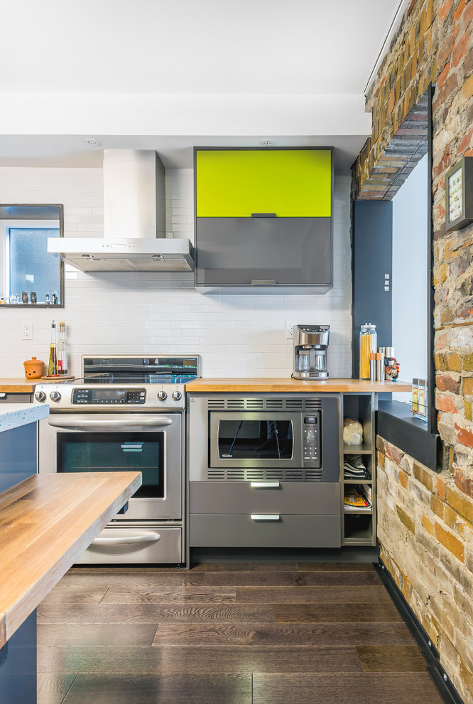 Contemporary open plan kitchen in Toronto with wood benchtops, white splashback, subway tile splashback, dark hardwood floors and with island.