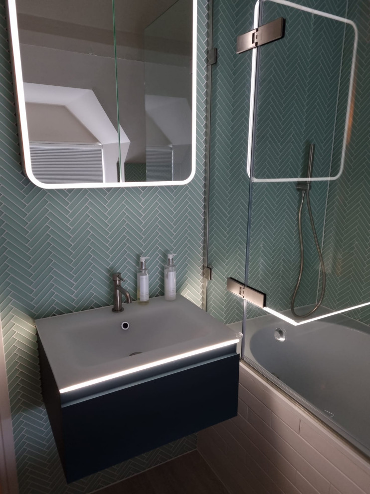 Example of a mid-sized trendy kids' blue tile and ceramic tile single-sink bathroom design in Gloucestershire with furniture-like cabinets, green cabinets, a wall-mount toilet, a wall-mount sink, glass countertops, a hinged shower door, white countertops and a floating vanity