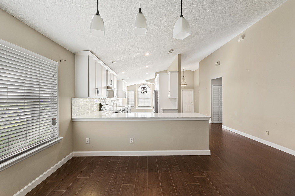 Large transitional l-shaped vinyl floor and brown floor open concept kitchen photo in Jacksonville with an undermount sink, shaker cabinets, blue cabinets, quartzite countertops, white backsplash, ceramic backsplash, stainless steel appliances and a peninsula