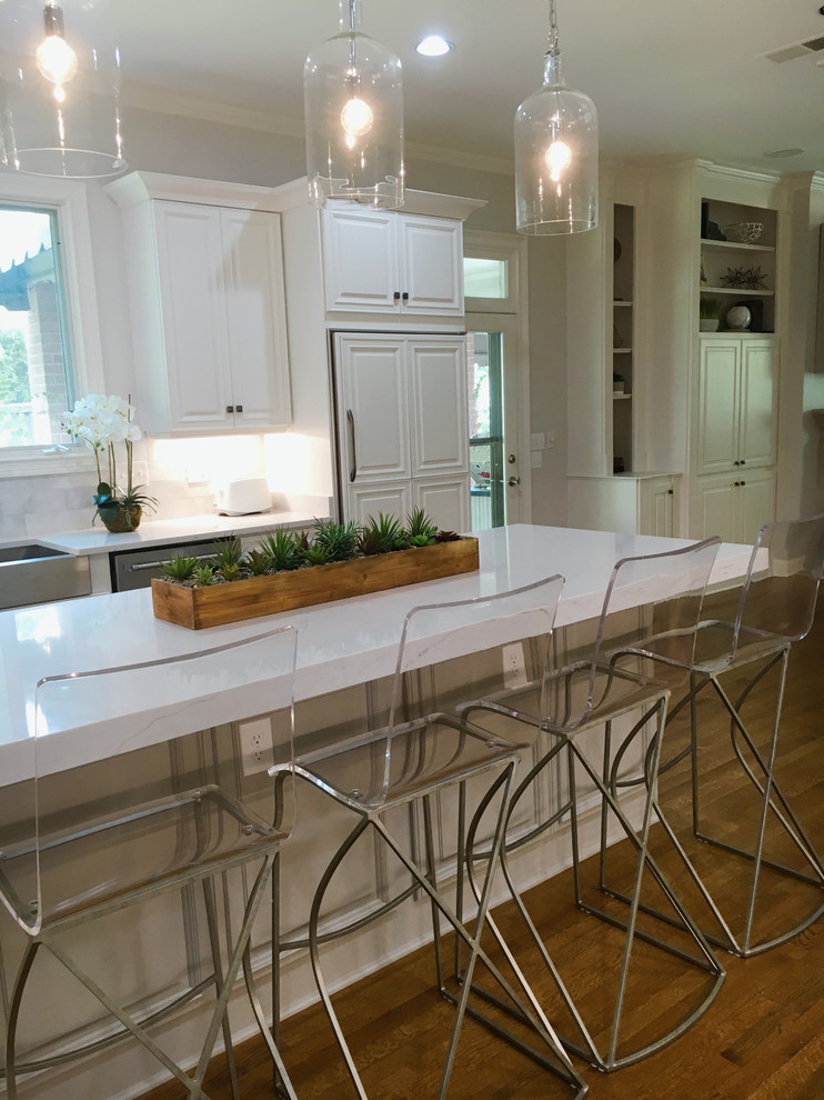 Inspiration for a mid-sized transitional l-shaped dark wood floor eat-in kitchen remodel with a farmhouse sink, raised-panel cabinets, white cabinets, solid surface countertops, white backsplash, stone tile backsplash, paneled appliances and an island