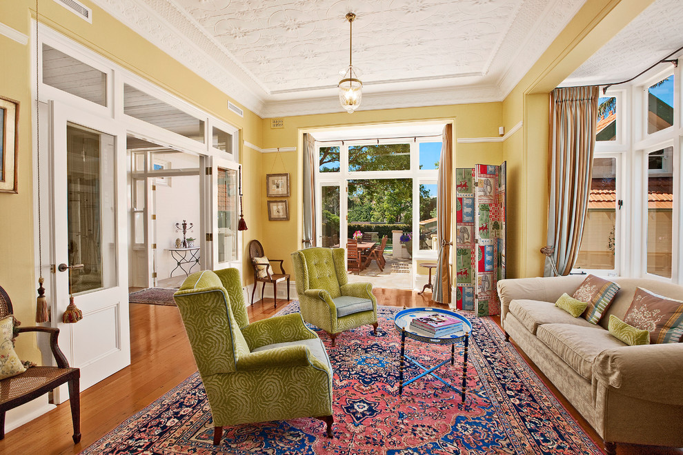 Mid-sized eclectic formal enclosed living room in Melbourne with yellow walls, light hardwood floors and no tv.